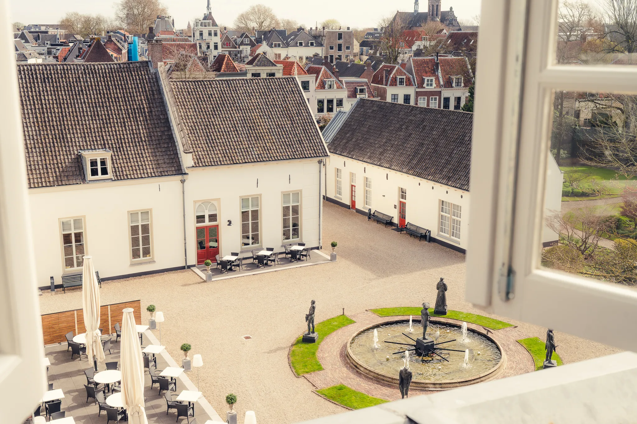 Uitzicht op de historische binnentuin van Grand Hotel Karel V in het centrum van Utrecht met fontein, terras en monumentale gebouwen in rustige omgeving